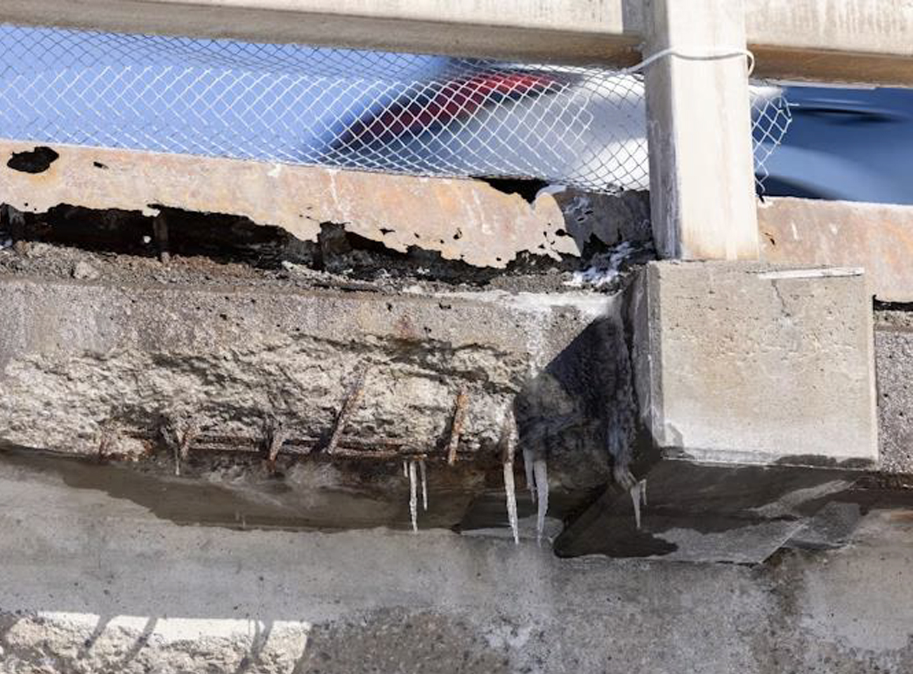 Close-up of concrete structure showing cracks and exposed reinforcing steel corroded by saltwater ingress.